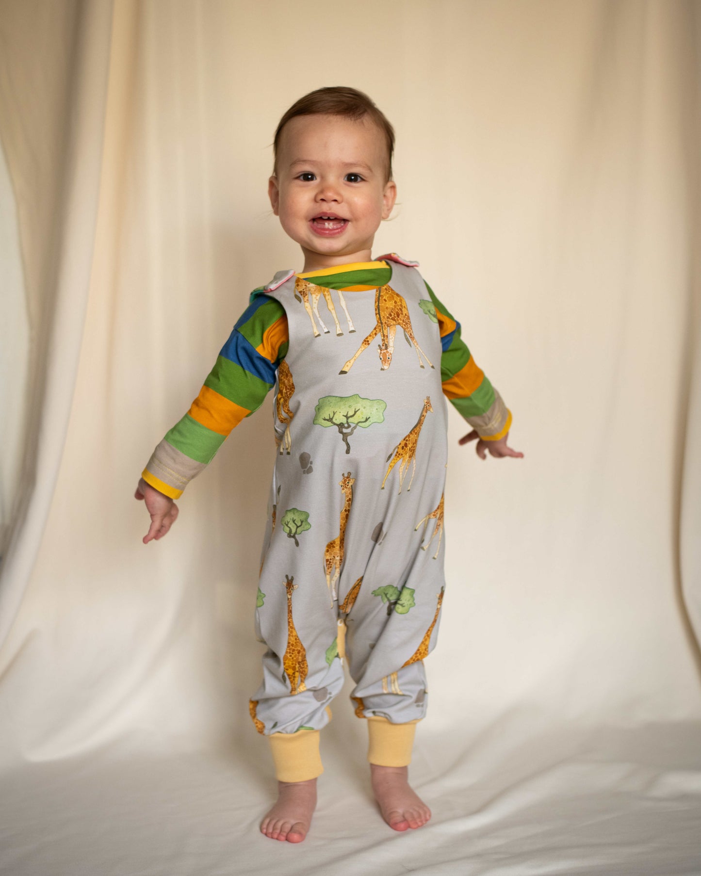 Child wearing ILO Giraffes Organic grow with Me Romper