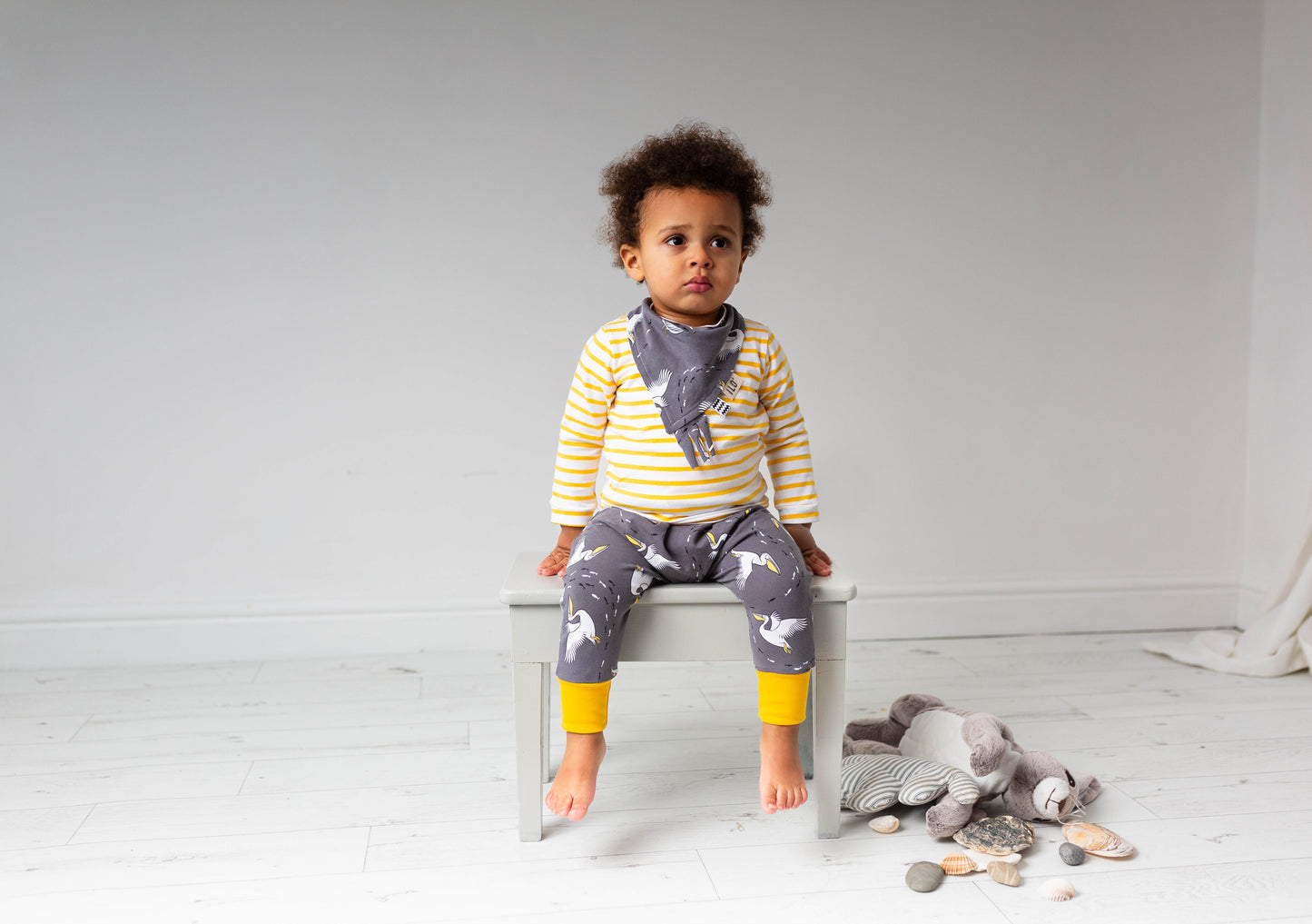 Child wearing Pelicans organic reversible taggy bib with fabric frill for sensory