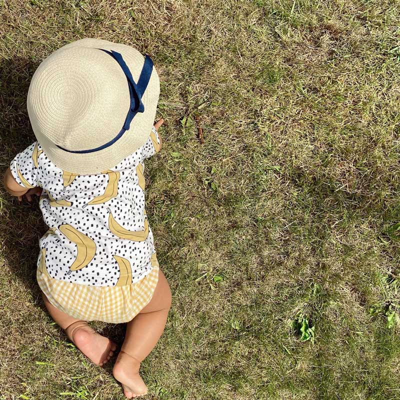 young child crawling on grass wearing a banana print tee