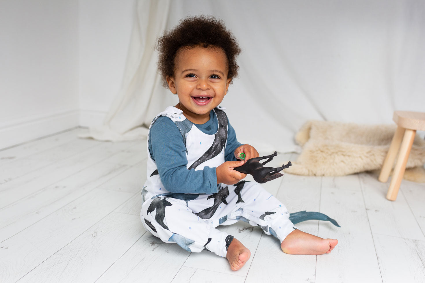 young child wearing whale print romper playing with toys in a white room ILO Clothing